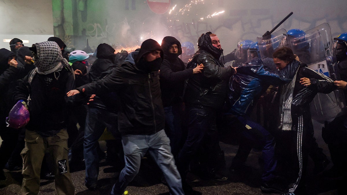 Fireworks fly as hooded protesters clash with police after Olympics open in Milan at george magazine