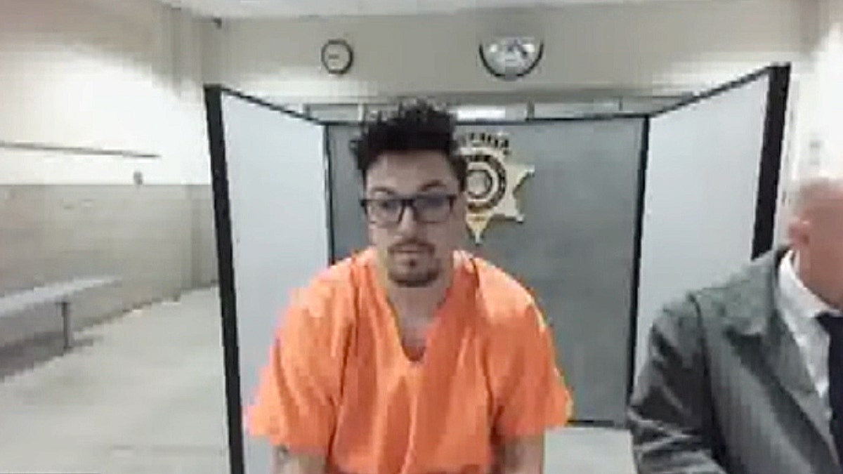 Former Pima County sheriff’s deputy Travis Reynolds appears in court wearing an orange jail uniform