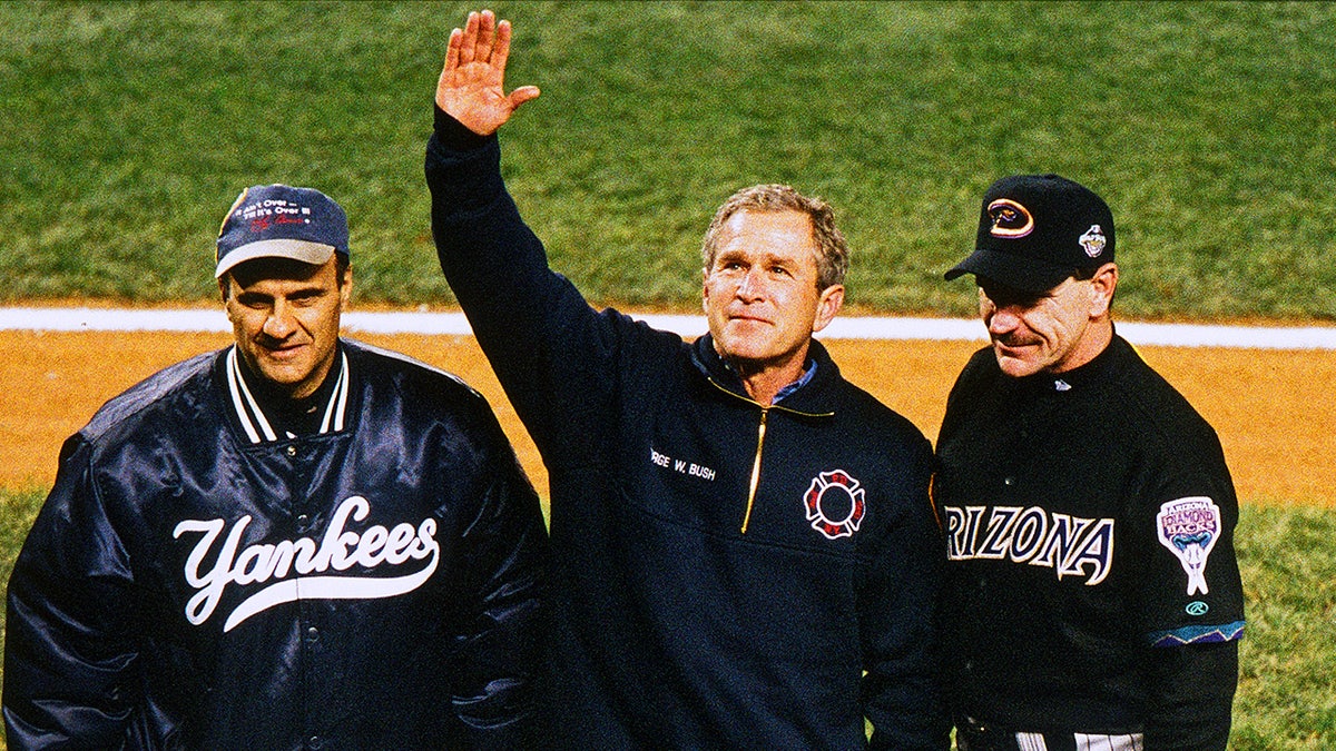 George W. Bush stands with Joe Torre and Bob Brenly on field before World Series game.