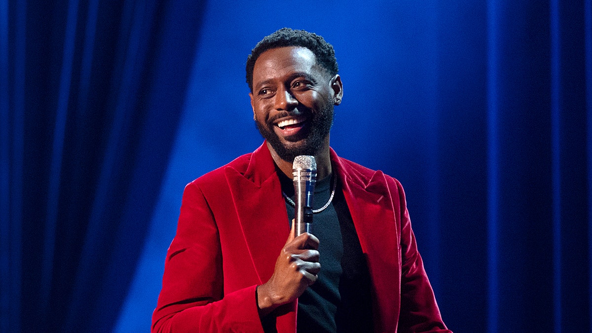 Comedian Kountry Wayne holds a microphone onstage.