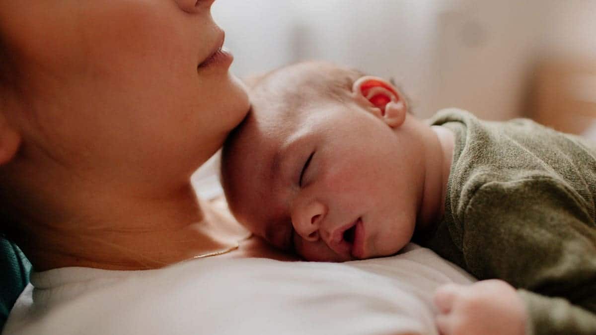 A sleeping infant rests on its mother's chest.