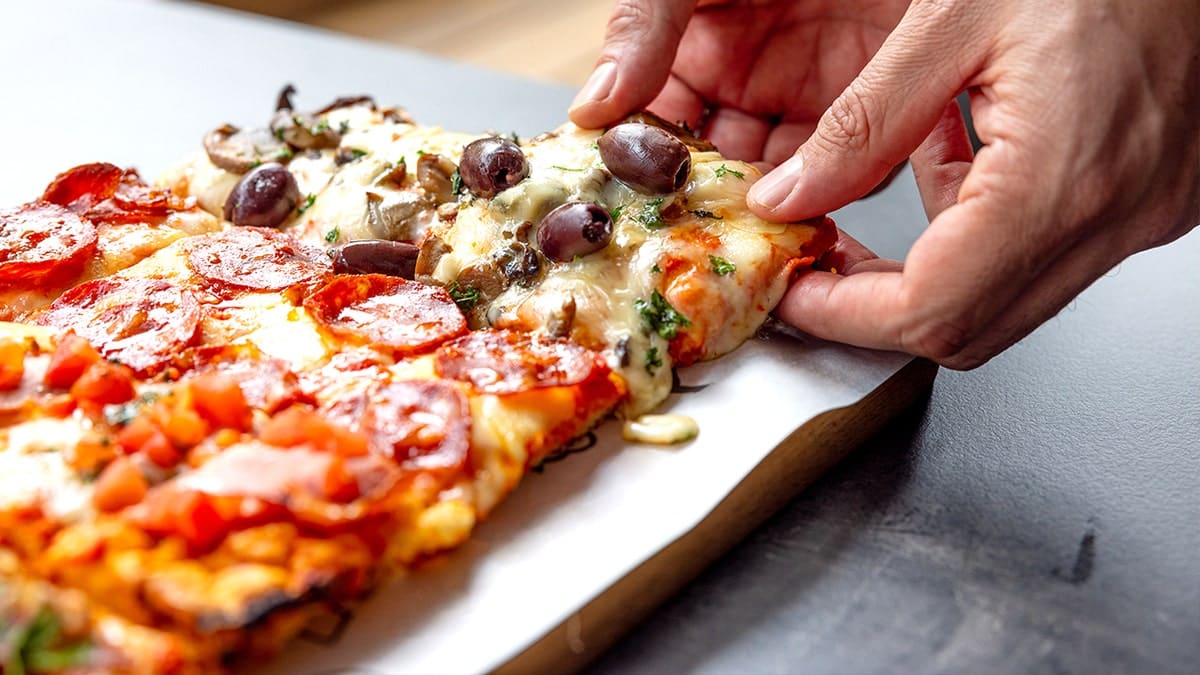 Person grabbing cheesy square pizza