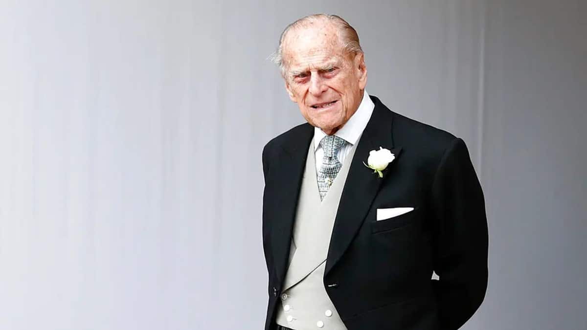 Prince Philip walking outside in a suit following a royal's wedding.