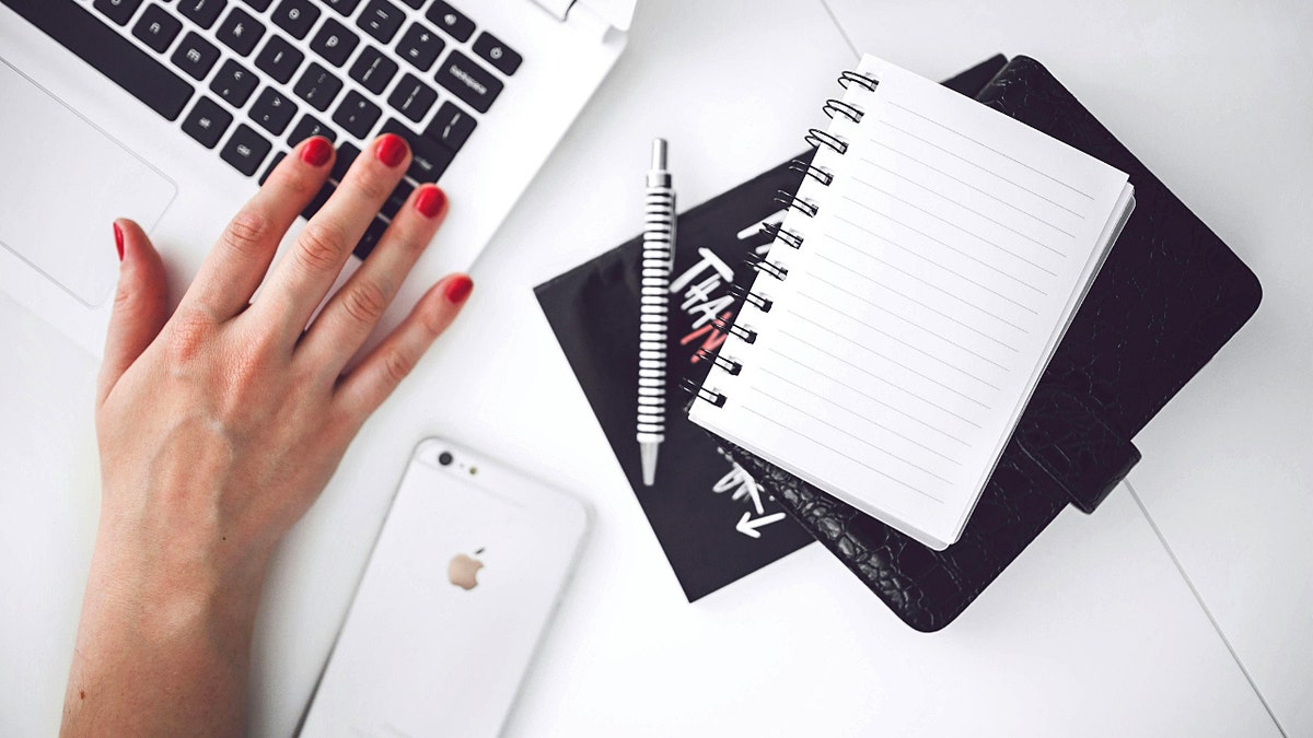A pile of notebooks next to a computer keyboard