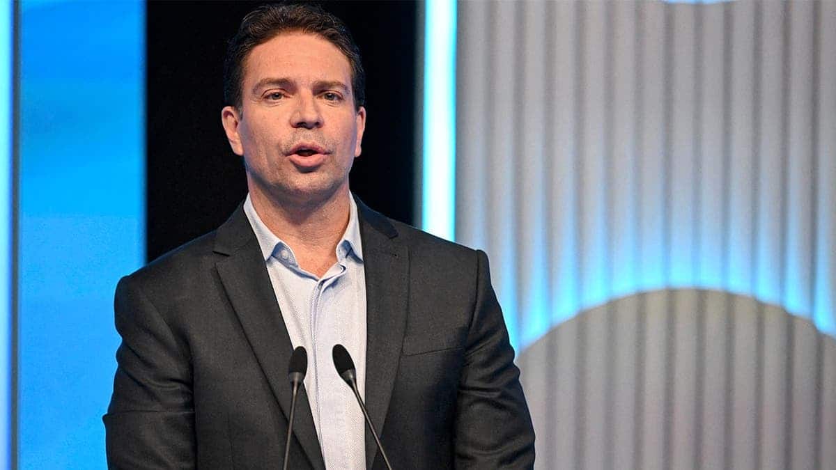 Alexandre Ramagem gestures with his hands while standing at a podium in a television studio.