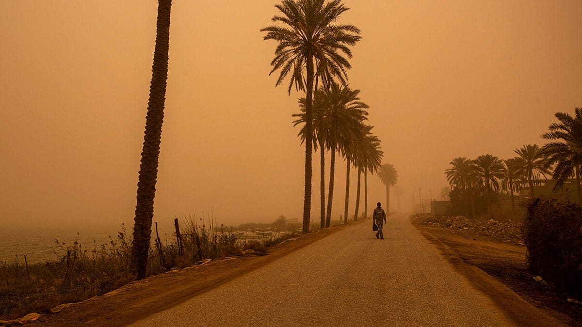 A man walking along a road during a sand storm in Basra, Iraq