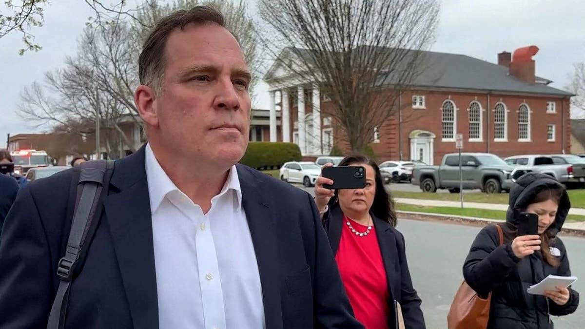 Former teacher walking into a court room with press behind him
