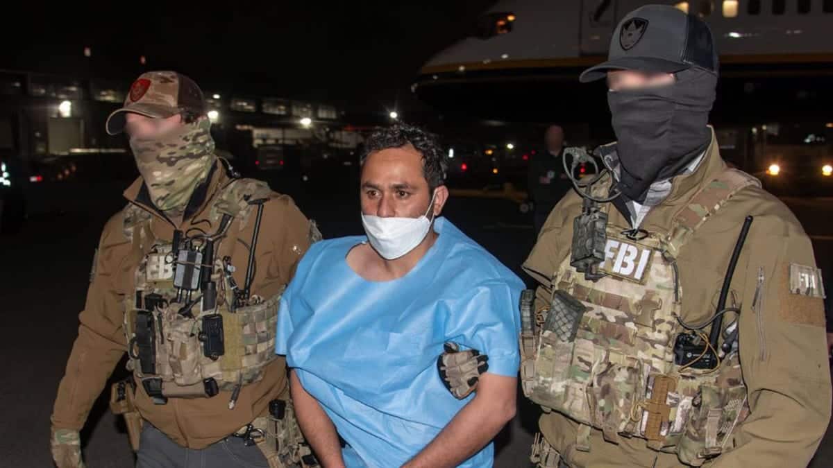 Muhammed Sharifullah in handcuffs standing with FBI Director Kash Patel