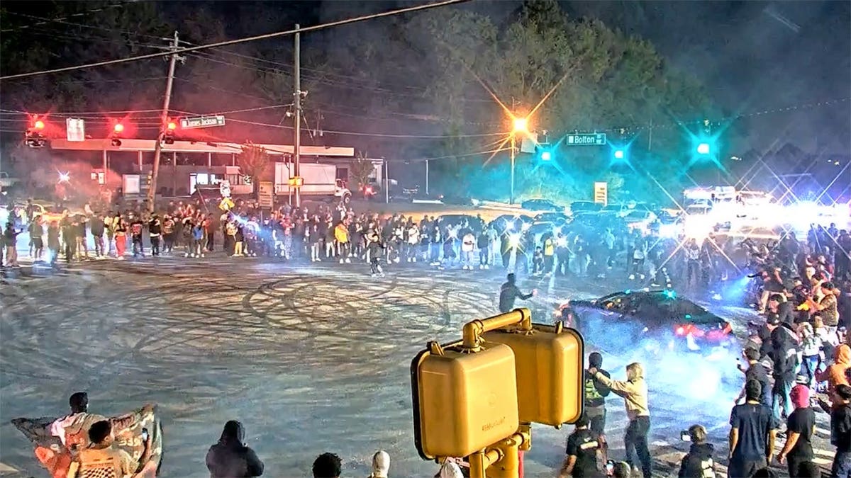 Spectators gathered at an intersection watching an illegal street racing takeover in Atlanta