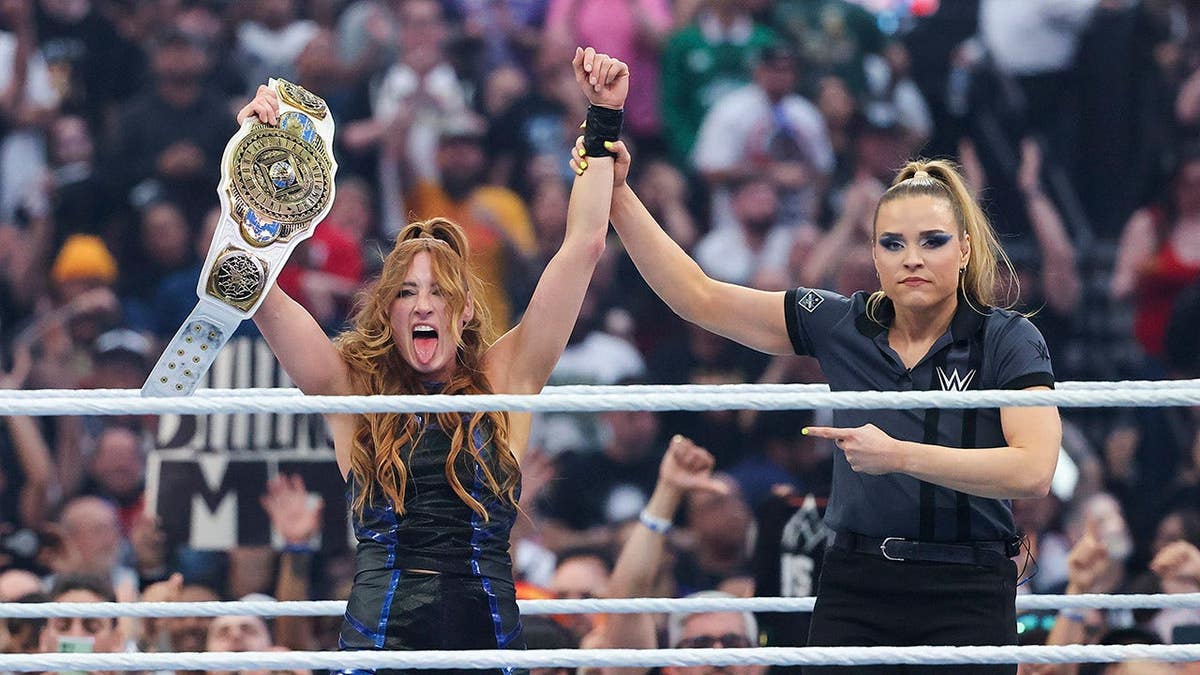 Becky Lynch holding championship belt celebrating in wrestling ring