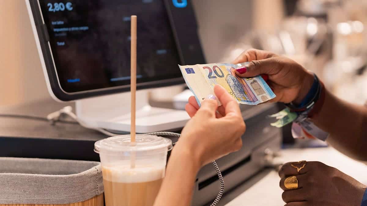 Customer making a contactless payment with euro banknotes at a coffee shop
