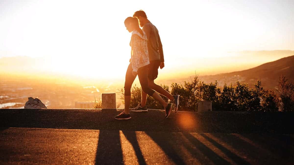 A couple walks along road at sunrise.
