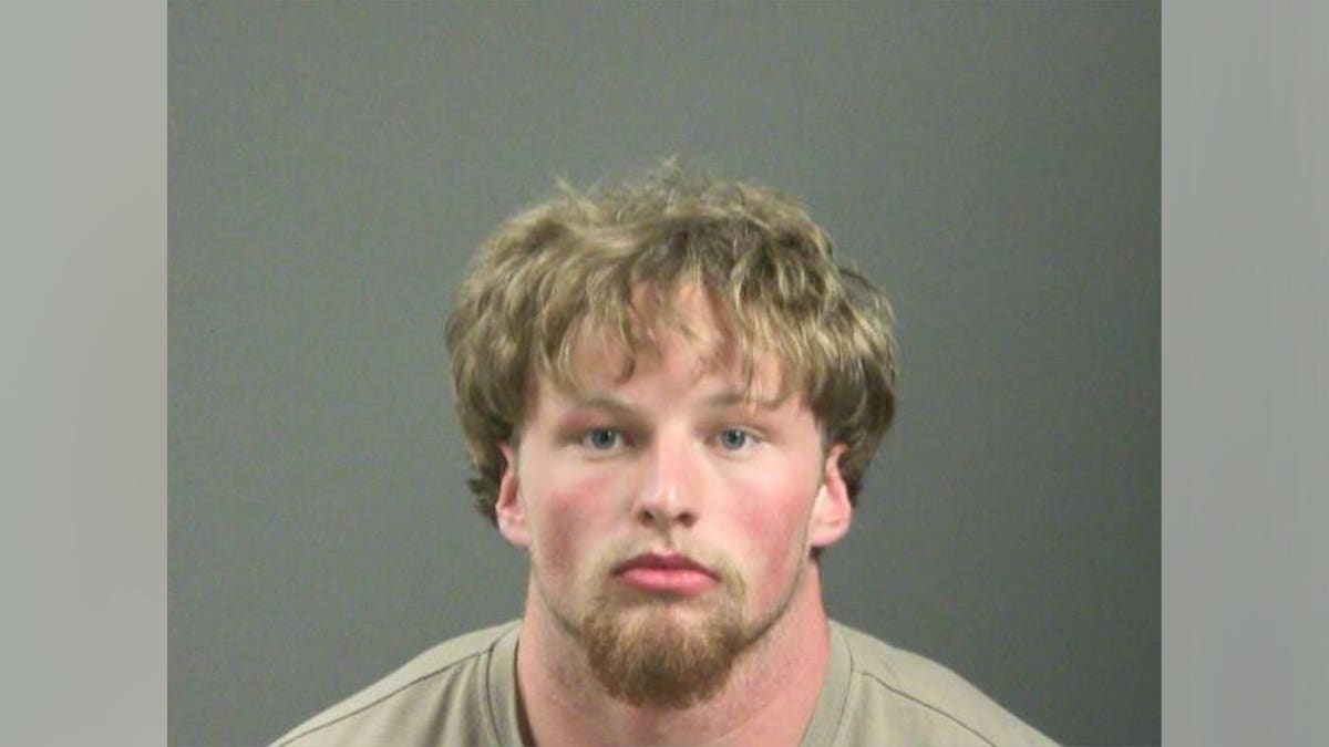 Crew Kvern standing in a mugshot photo