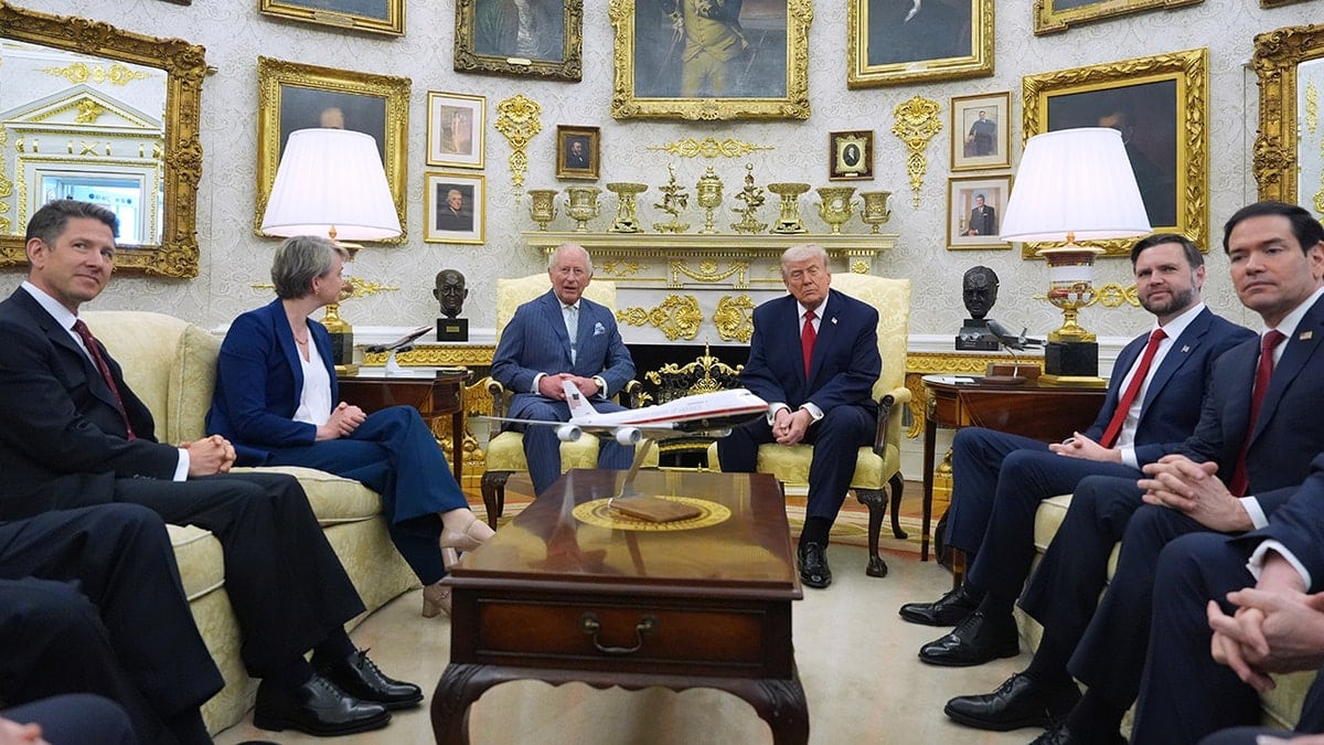 President Donald Trump and King Charles III standing in the Oval Office with officials