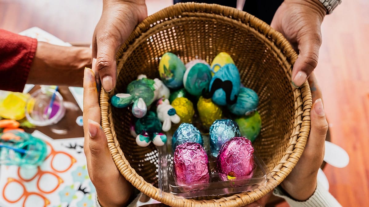 Family member's hands holding easter basket filled with candy and festive items