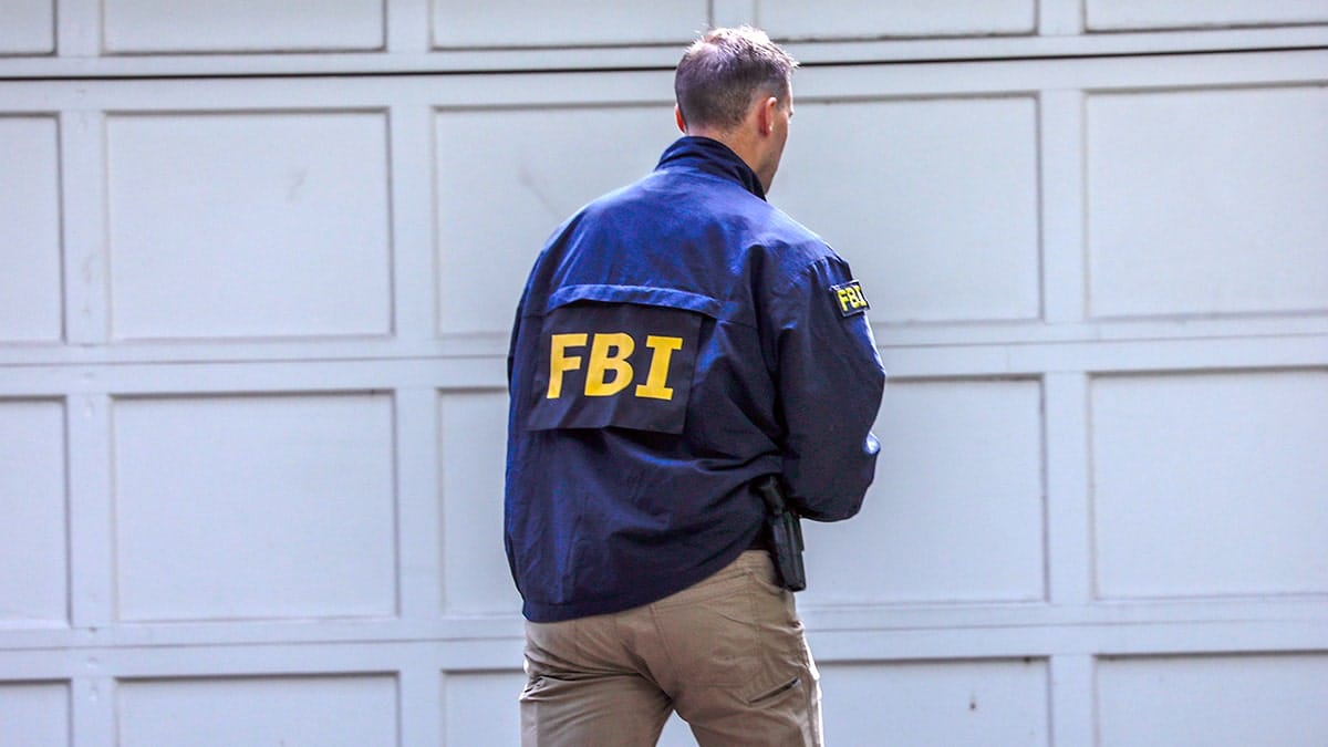 An man faces away from the camera with an FBI jacket on.
