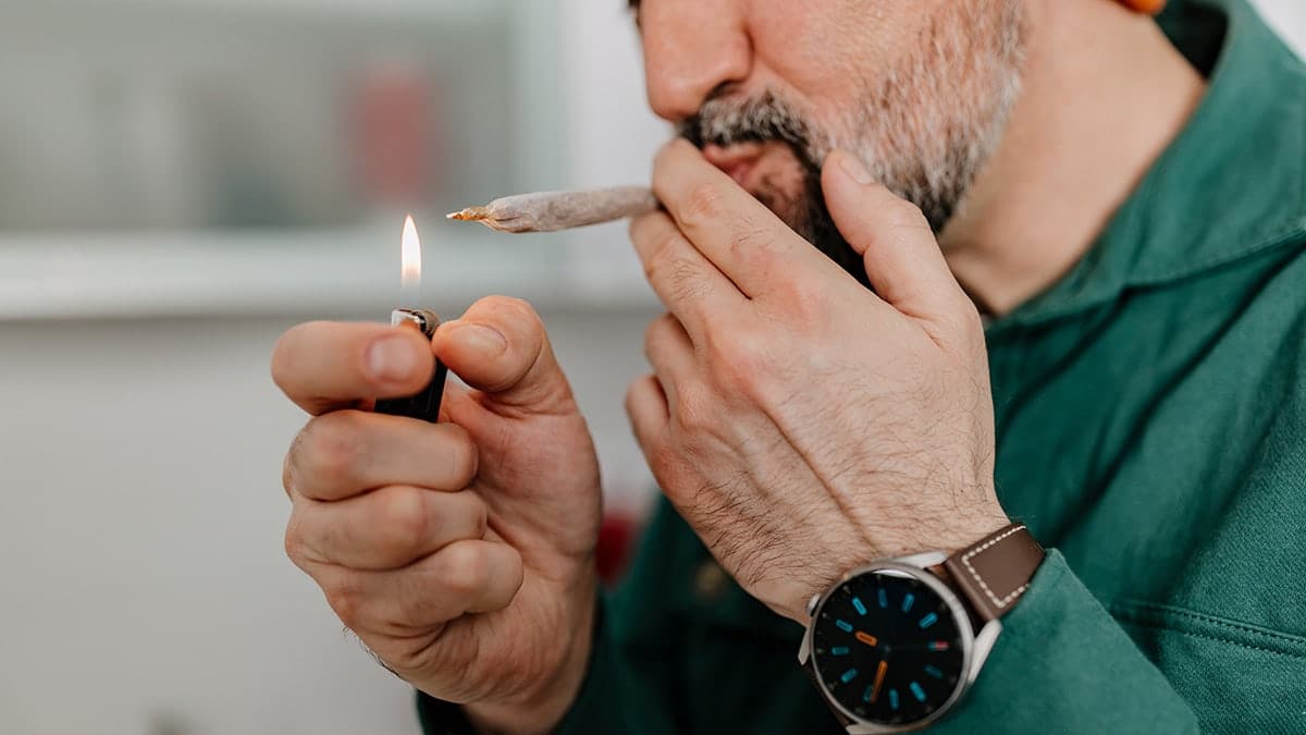 man taking a hit of marijuana joint