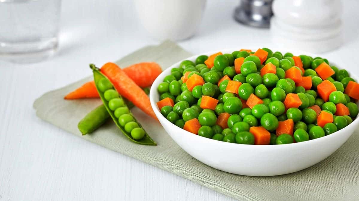 Fresh bowl of green beans and cubed carrots on white background