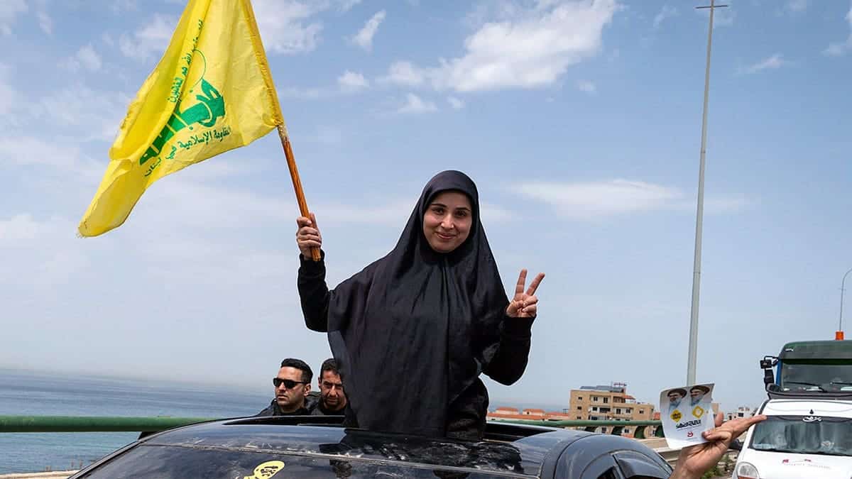 A woman waves a Hezbollah flag among people traveling south near Saida in Lebanon