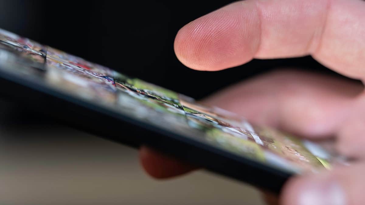 Person using smartphone holding deceptive tracking link message.