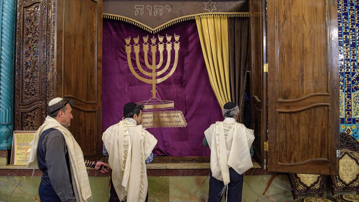 02/13/2020 Tehran, Iran. Iranian Jewish men unveil their much adorned holy scroll from chamber Aron Kodesh, as a part of their daily prayer in a synagogue, Tehran.