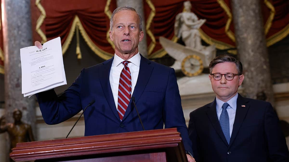Senate Majority Leader John Thune holding a bill speaking with Speaker Mike Johnson in U.S. Capitol