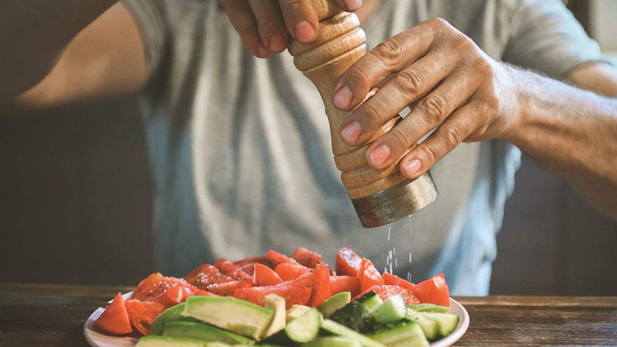 man salts fresh vegetables