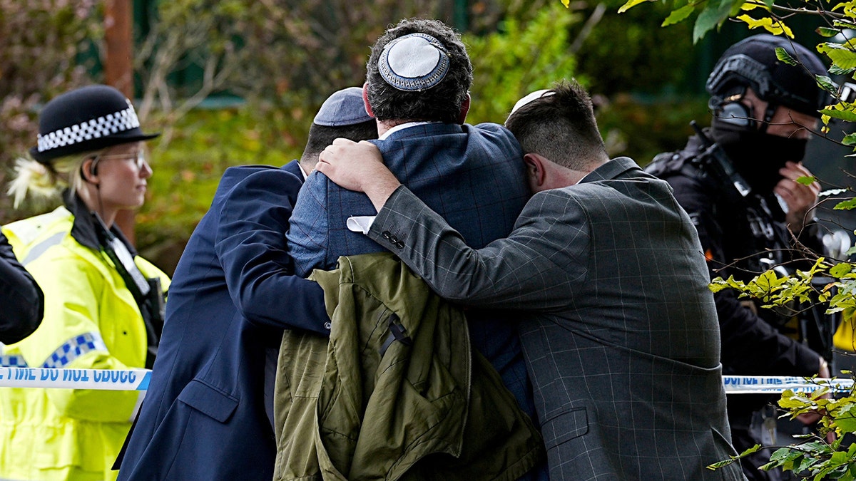 Members of the Jewish community comforting each other near Heaton Park Hebrew Congregation synagogue in Manchester