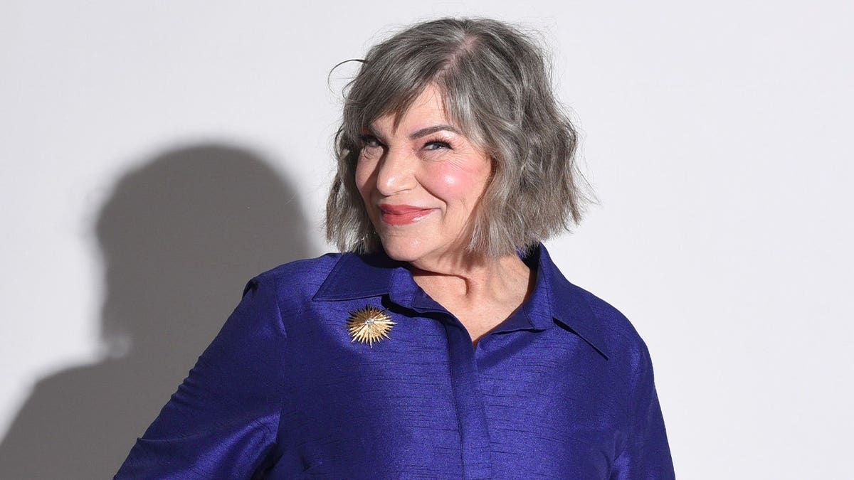 Mindy Cohn poses in a purple dress.