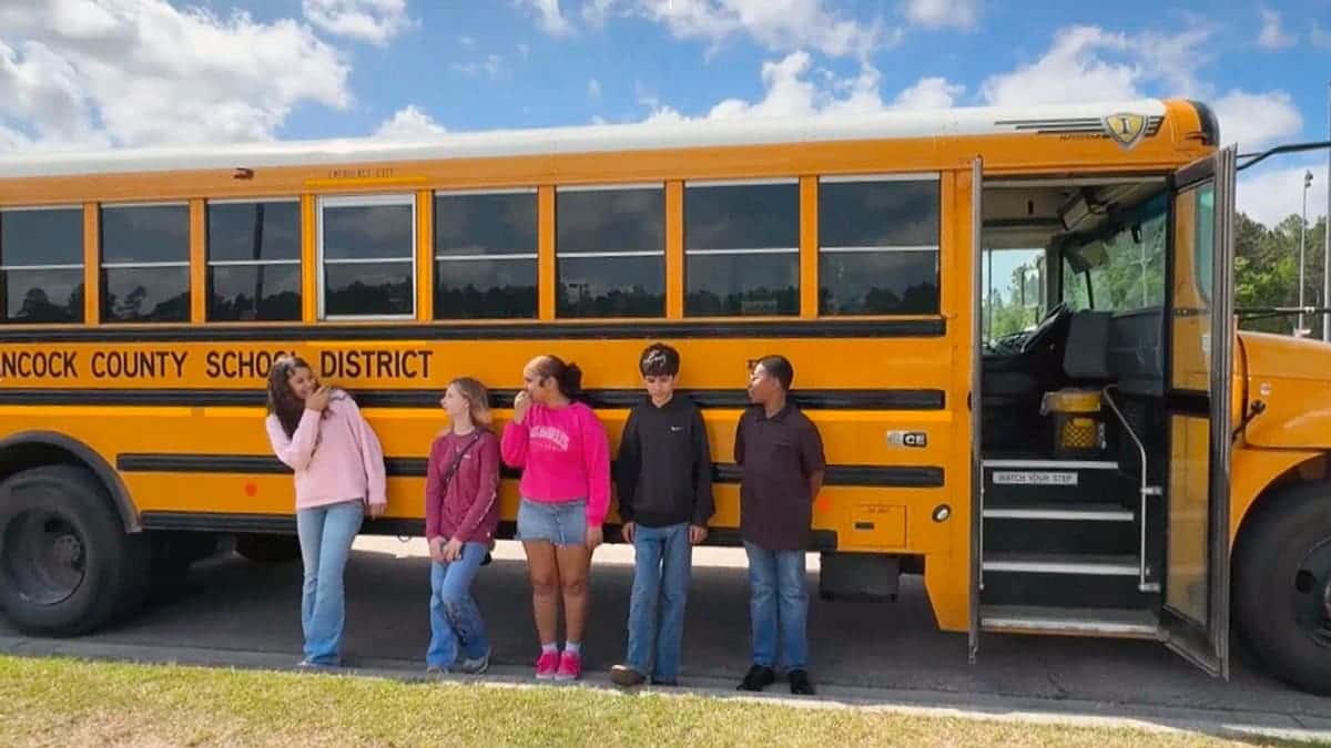 Mississippi middle school students stand next to a bus