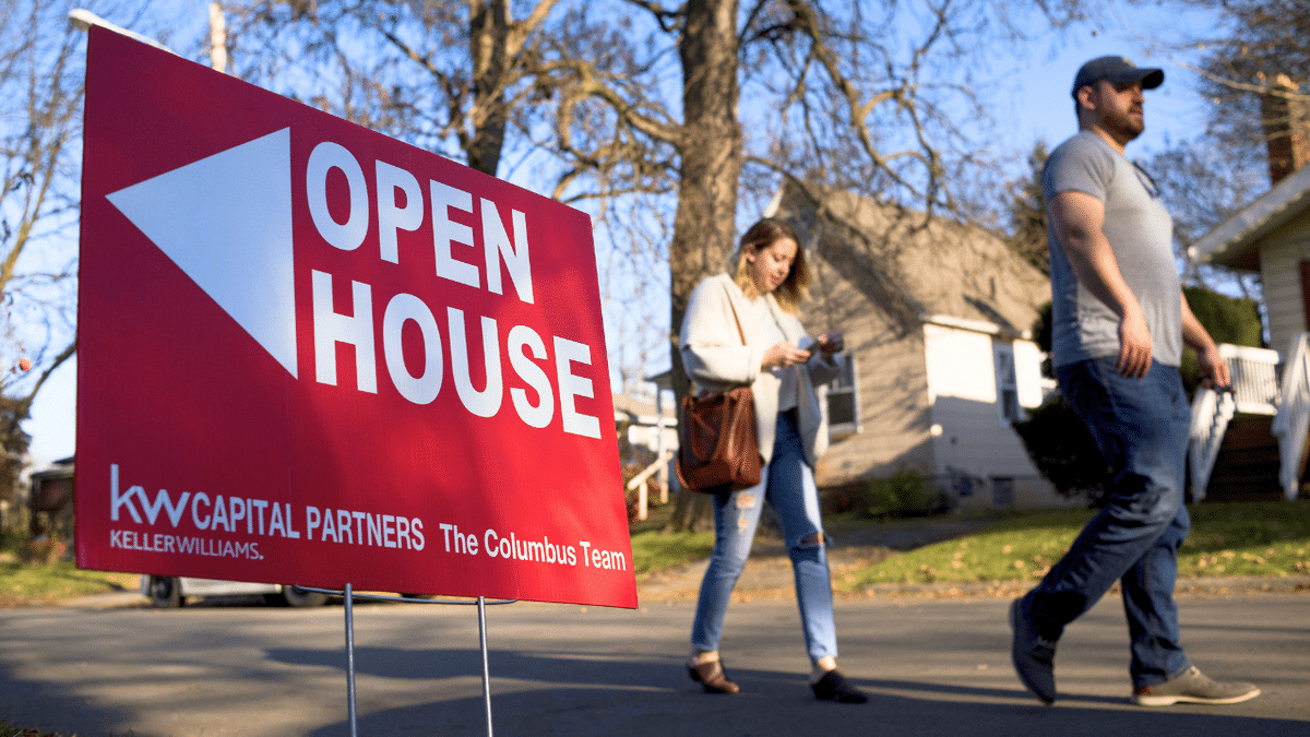 People are seen walking near an 'Open House' sign in Columbus, Ohio.