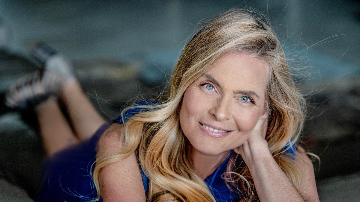 Kim Alexis smiling wearing a blue top and posing for a photo.