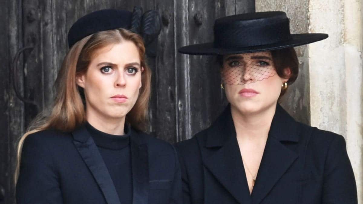 Princess Beatrice and Princess Eugenie standing together at a funeral wearing black