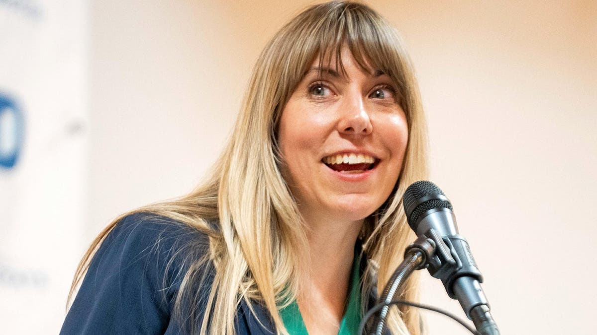 Sarah Trone Garriott speaks into a microphone while standing at a podium.