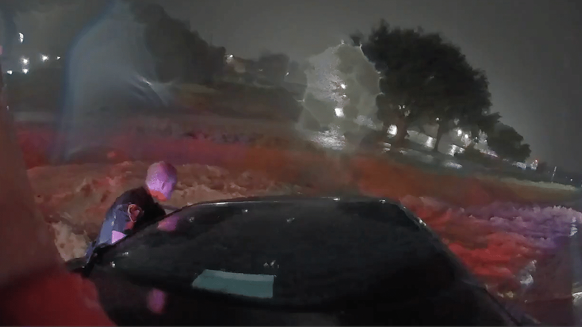 Officer leans into stranded car in floodwaters during Texas rescue captured on bodycam.