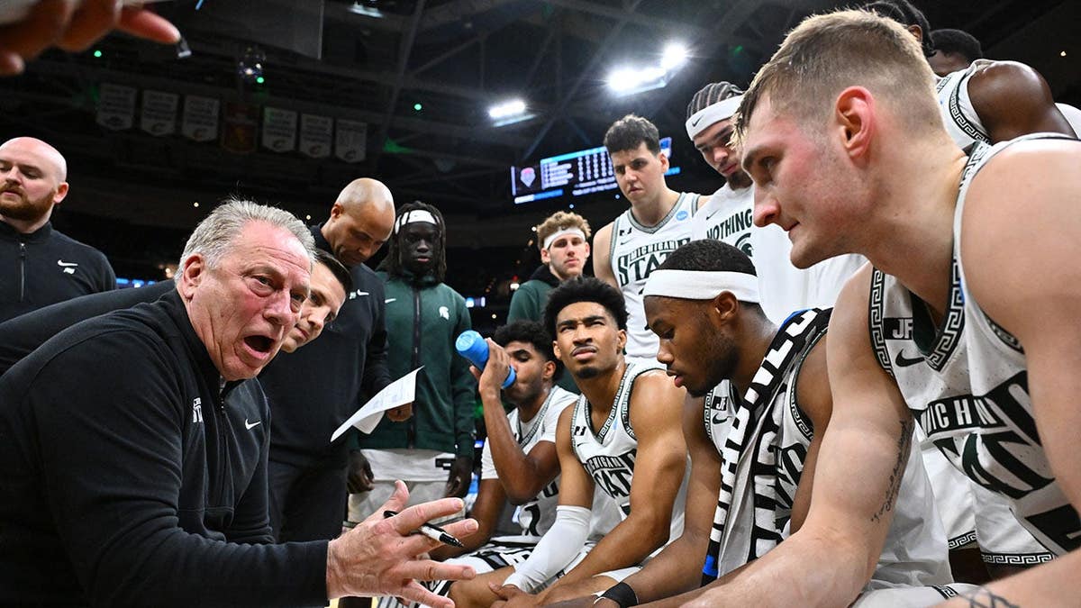Head coach Tom Izzo talks in the huddle during a basketball game.