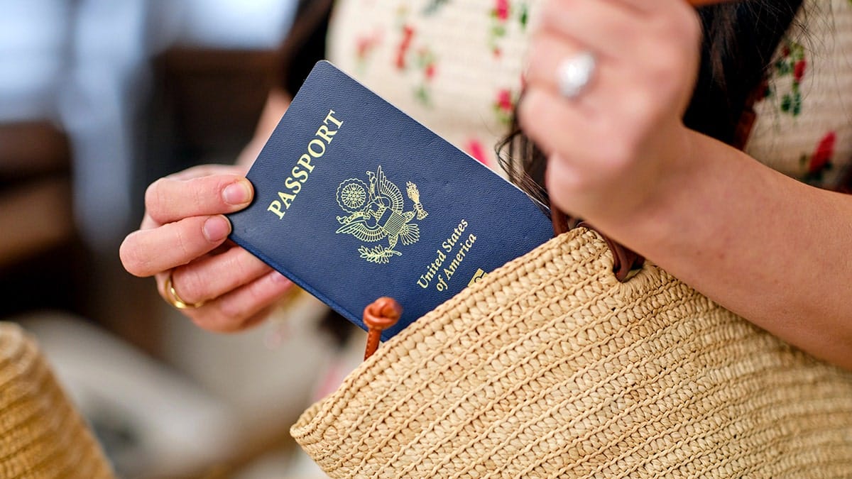 A woman pulls a passport out of her purse.