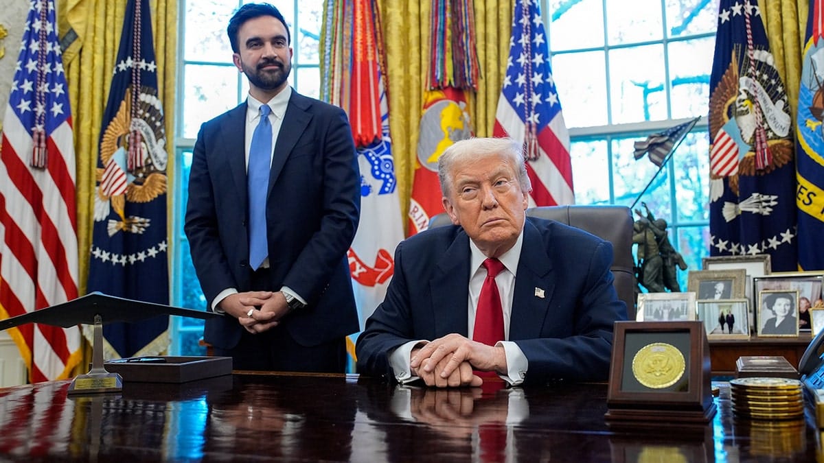 Zohran Mamdani stands next to President Donald Trump, who is sitting at desk in Oval Office