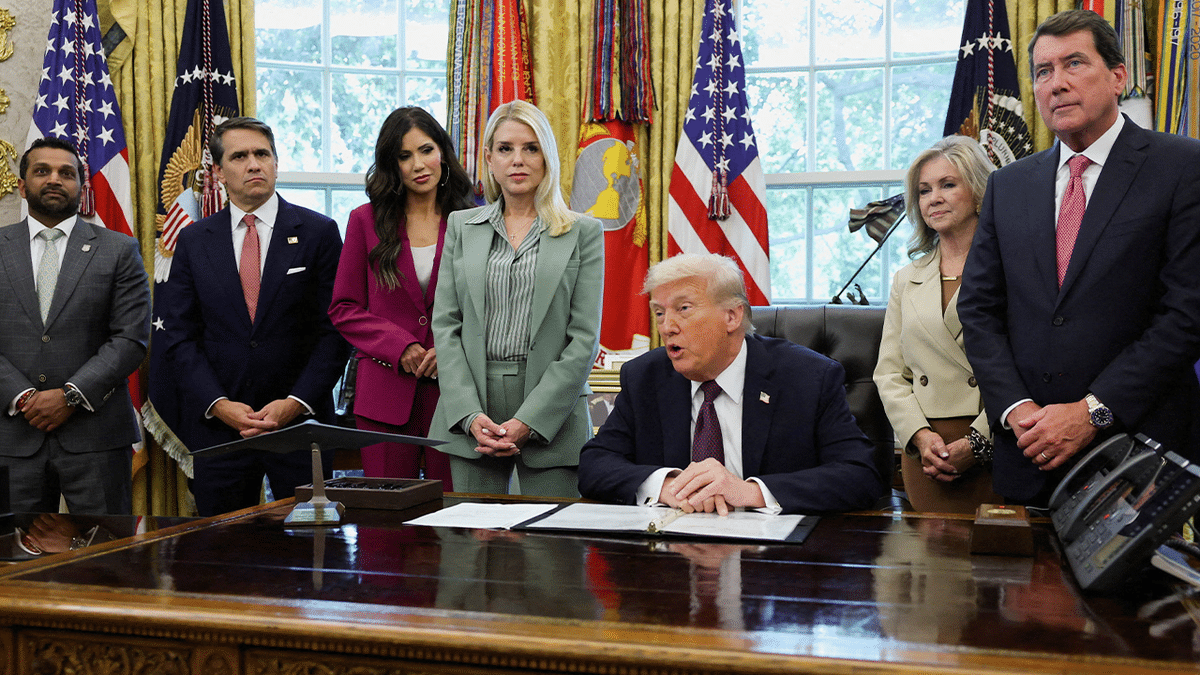 President Donald Trump signing a memorandum in the Oval Office with officials including FBI Director Kash Patel