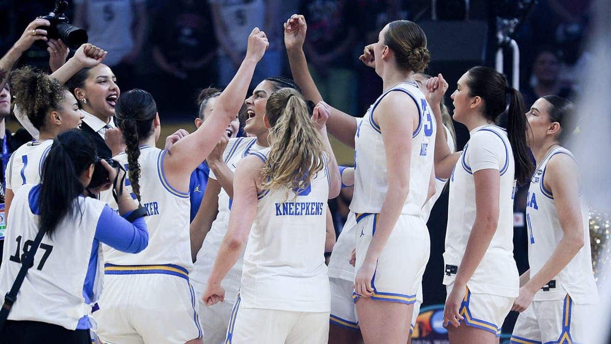UCLA Bruins women's basketball team huddling on court before game.