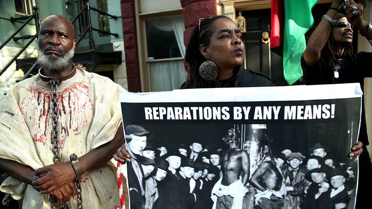 People holding signs supporting reparations