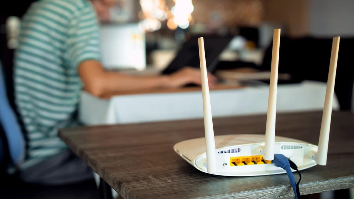 A Wi-Fi router sits near a woman working on a laptop.