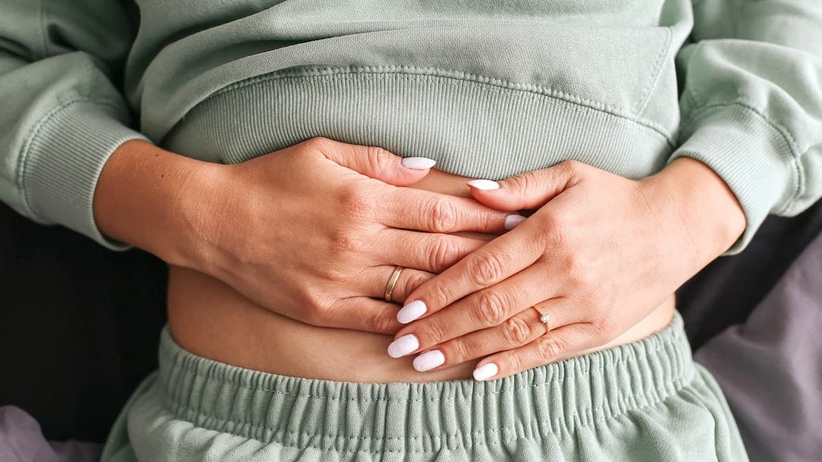Woman holding her stomach with both hands showing discomfort