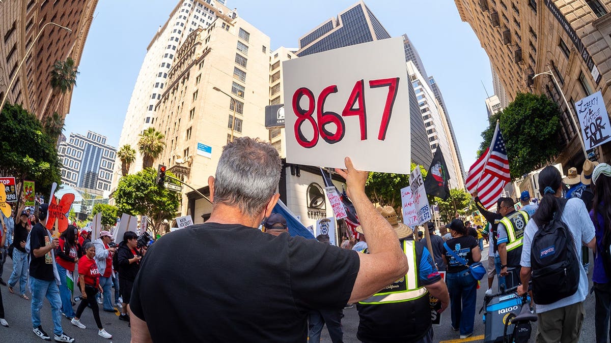 Person holds sign with '86 47' message on it