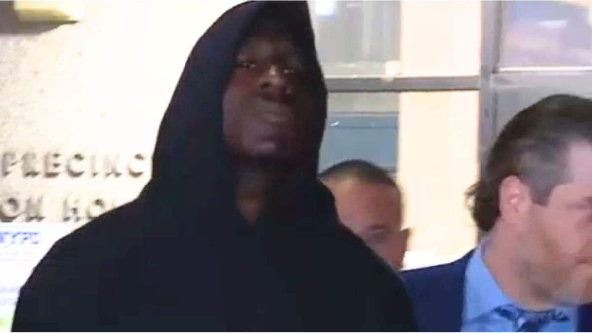 Rhamell Burke stares into a camera as NYPD detectives detain him