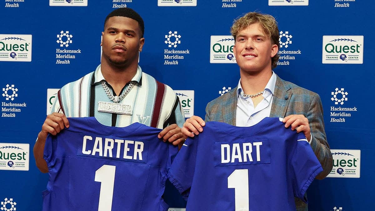 Abdul Carter and Jaxson Dart holding up New York Giants jerseys at a press conference
