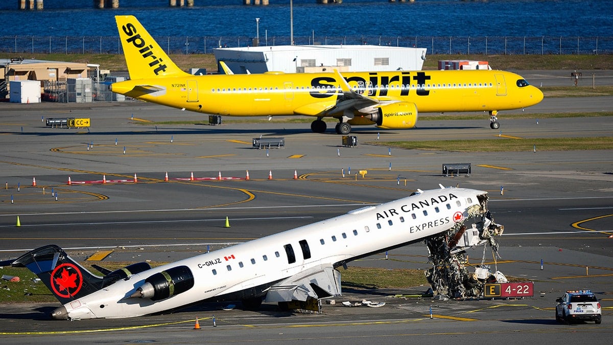 An Air Canada Express plane with a severed cockpit resting on a runway near a damaged airport vehicle