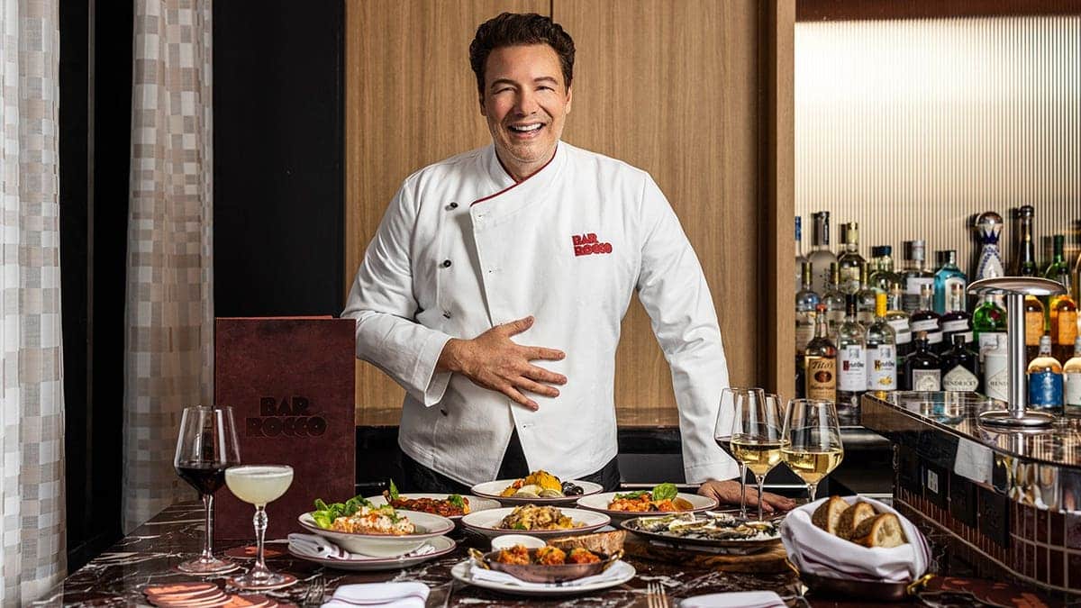 Rocco DiSpirito poses in front of his dishes at Bar Rocco
