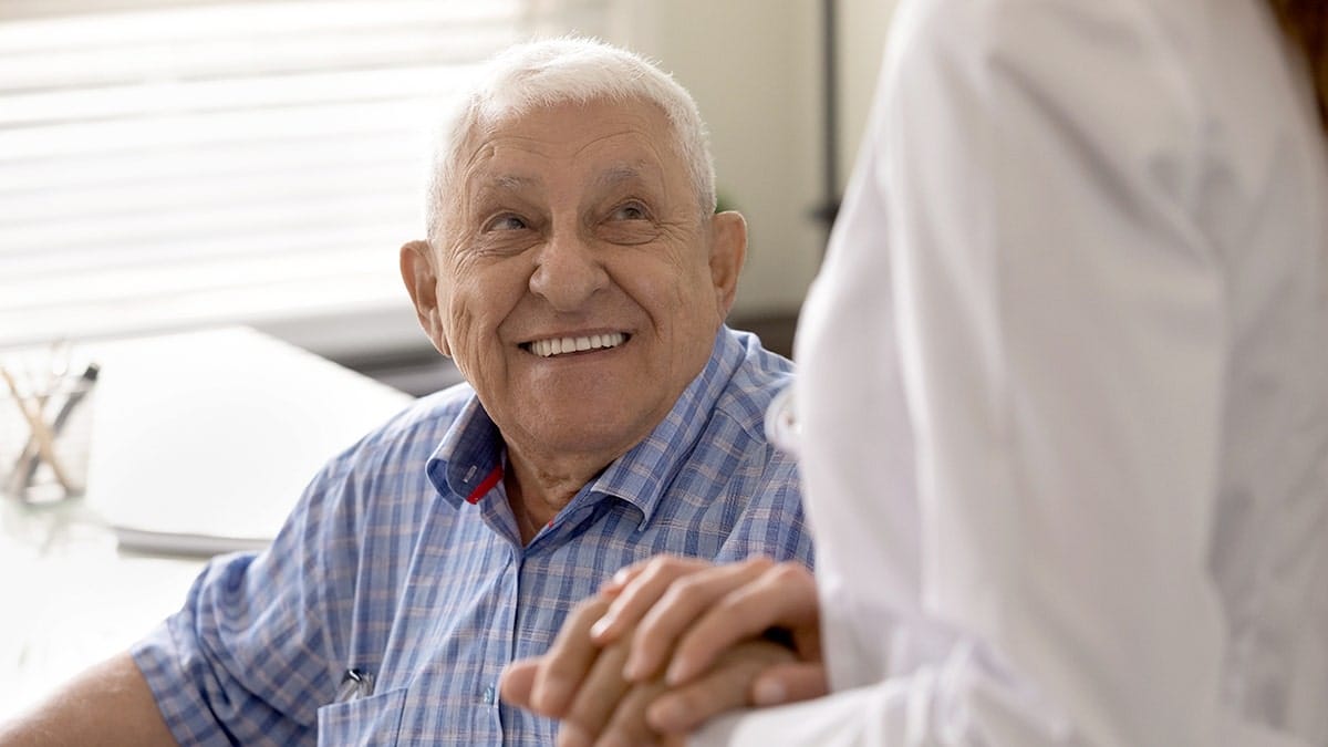 Doctor holding hands with a dementia patient and caregiver in a clinical setting