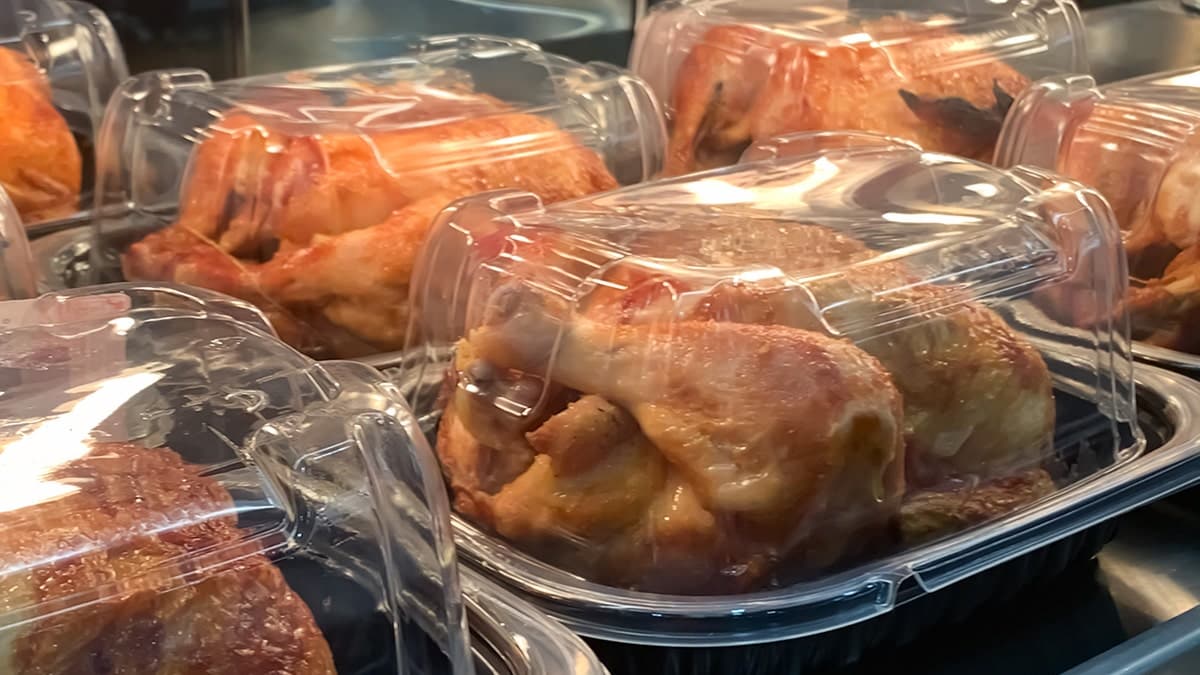 Packaged rotisserie chickens placed on supermarket deli shelf